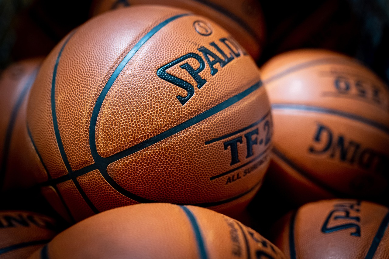 A close up of orange/brown basketballs, with black print in the grooves an on text