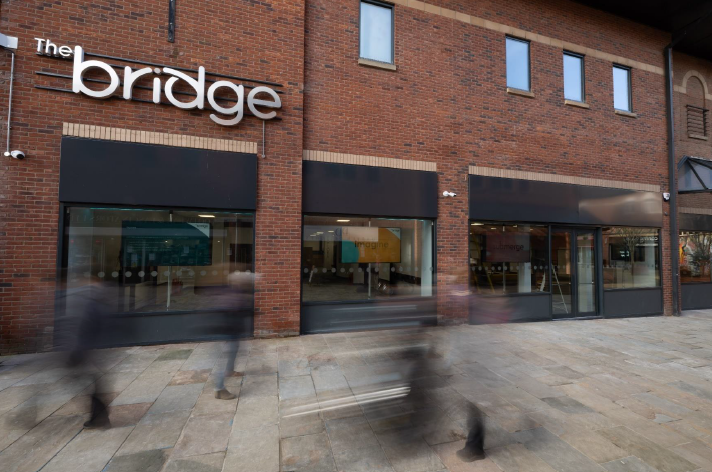 Photo of exterior of the Bridge, a red brick building with large, shopfront-style, windows with grey panels above